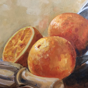 Still life of a bowl on its side with 3 full oranges and one orange that has been cut in half and juiced. There is a wooden juice reemer on the left hand-side.
