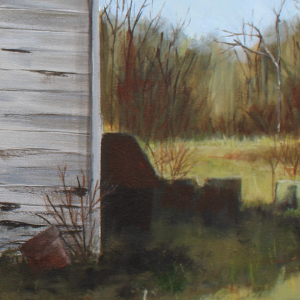 Side of an abandoned house with whitish-grey siding. There are shadow on the house, but the background is lit by streams of sunlight.